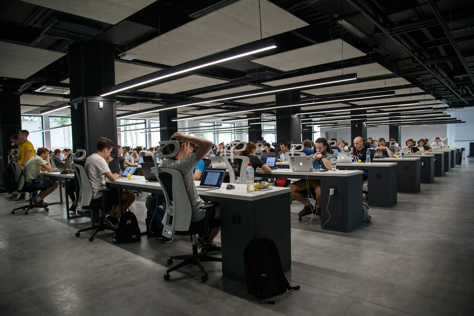 Open-plan office with people working at shared desks, representing collaborative delivery.